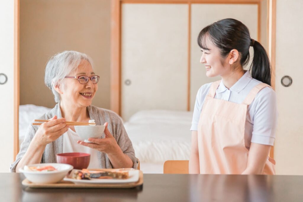 高齢者の食事を見守る介護スタッフ